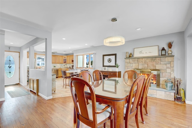 dining space featuring recessed lighting, baseboards, light wood-style floors, and a stone fireplace