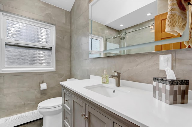 full bathroom with vanity, a stall shower, tile walls, toilet, and baseboard heating