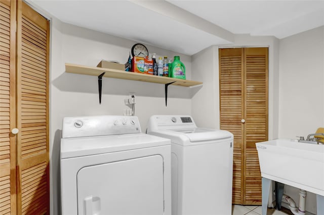 laundry room featuring washer and dryer, light tile patterned flooring, laundry area, and a sink