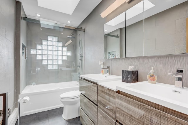 full bathroom with vanity, a skylight, tile walls, toilet, and tile patterned floors