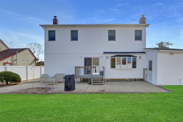 back of house with a lawn, a patio area, fence, and a chimney