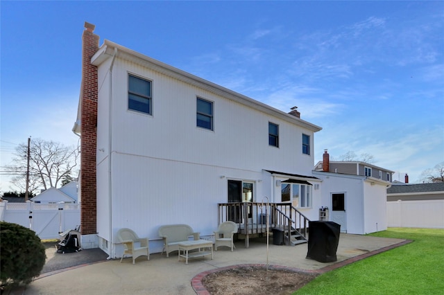 rear view of property featuring a lawn, a chimney, a fenced backyard, a patio, and a gate