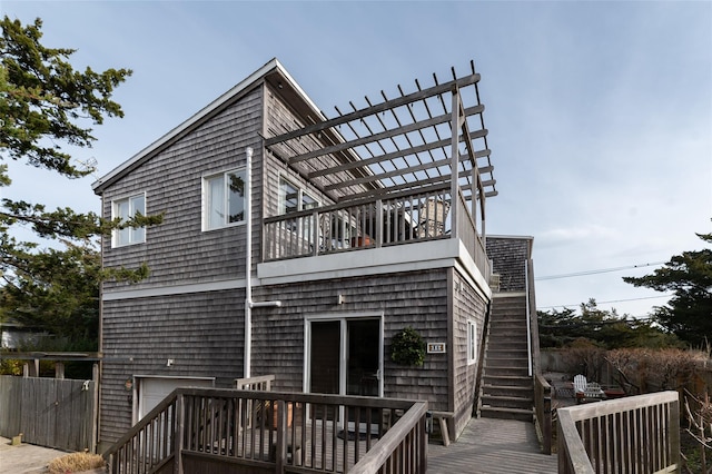 back of property featuring stairway, a balcony, fence, a wooden deck, and a pergola