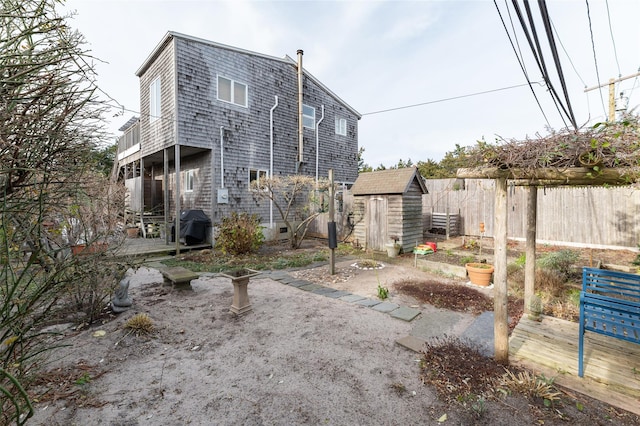 rear view of house with a deck, fence, an outdoor structure, and a shed