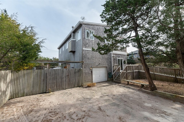 view of side of home with driveway, stairs, a garage, and fence