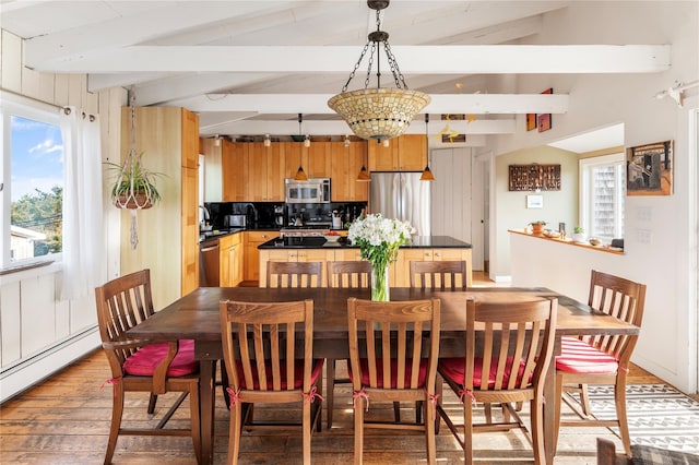 dining room with light wood finished floors, lofted ceiling with beams, and a baseboard radiator