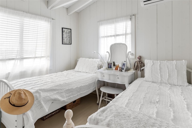 bedroom with beam ceiling and wood finished floors