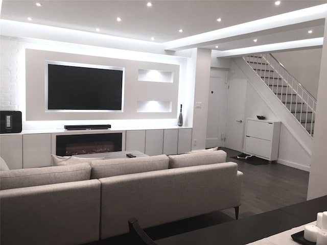 living area with recessed lighting, stairway, wood finished floors, and a glass covered fireplace