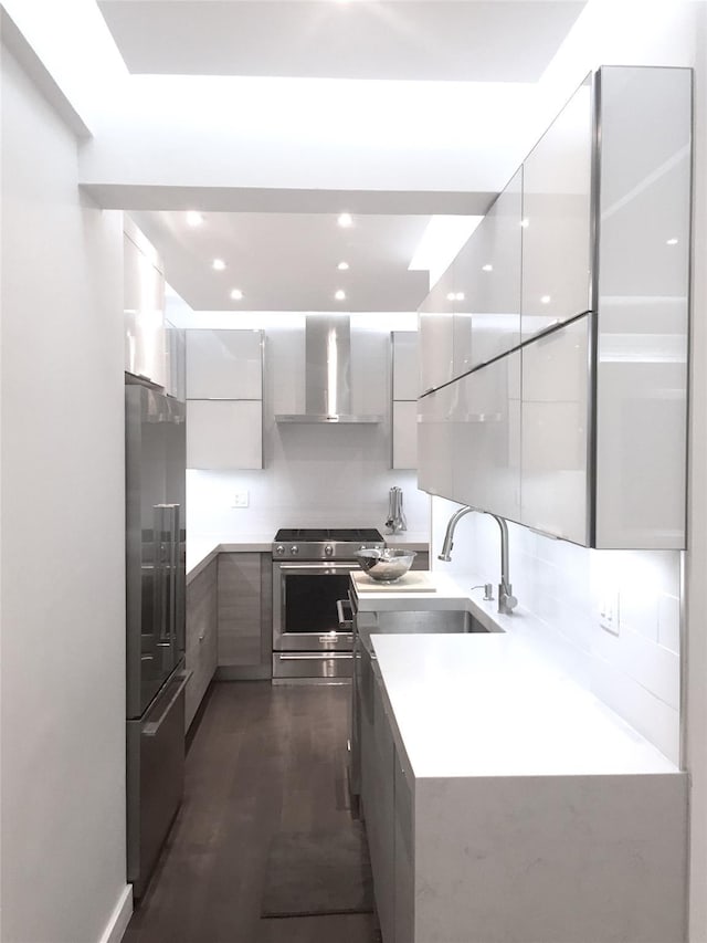 kitchen featuring appliances with stainless steel finishes, modern cabinets, light countertops, and wall chimney range hood