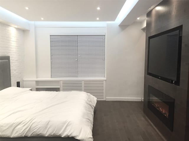 bedroom with recessed lighting, baseboards, a large fireplace, and dark wood finished floors