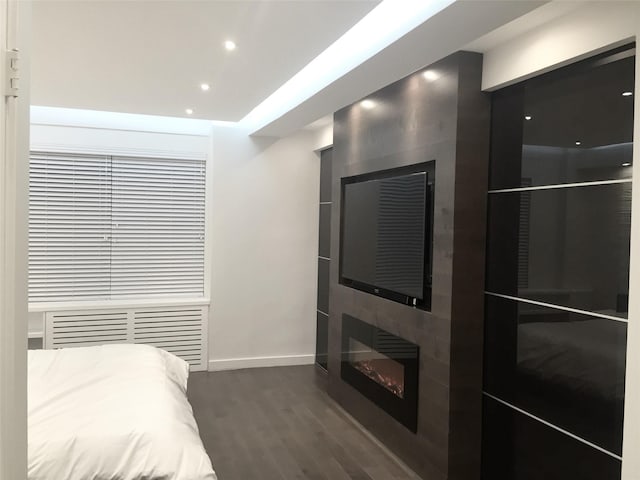 bedroom with a fireplace, recessed lighting, dark wood-style floors, and baseboards