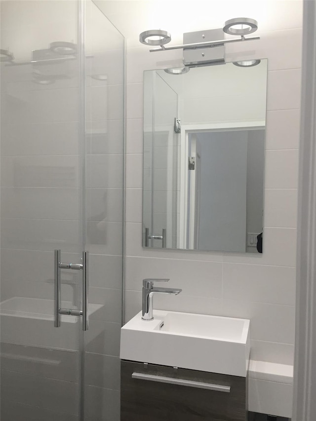 bathroom with tasteful backsplash, tile walls, a stall shower, and vanity