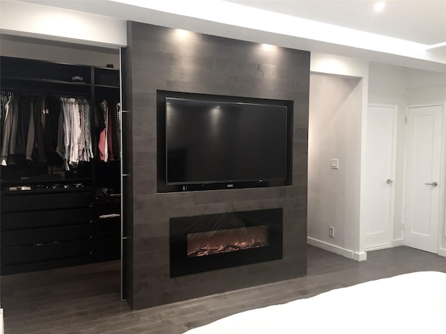 bedroom featuring a closet, a large fireplace, baseboards, and wood finished floors