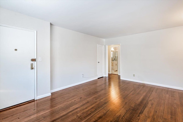 spare room with baseboards and wood finished floors