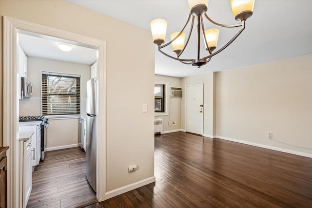 kitchen featuring radiator, dark wood finished floors, appliances with stainless steel finishes, a notable chandelier, and tasteful backsplash