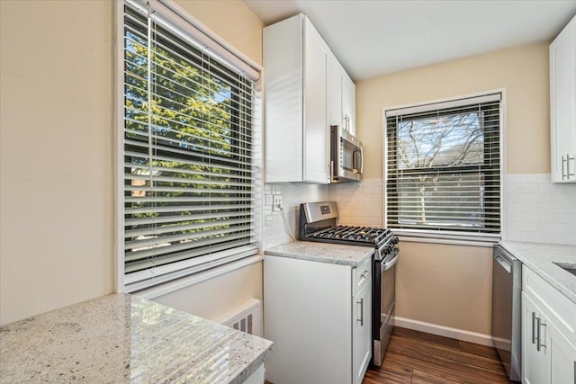 kitchen with dark wood finished floors, a healthy amount of sunlight, appliances with stainless steel finishes, and backsplash