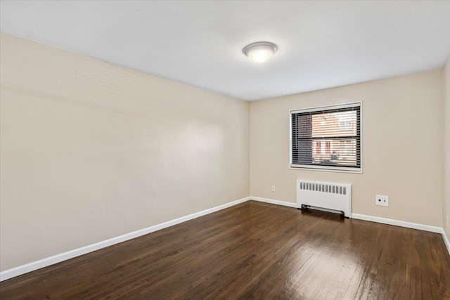 spare room with baseboards, radiator, and hardwood / wood-style floors