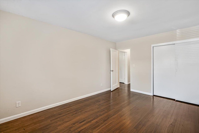 unfurnished bedroom featuring a closet, baseboards, and wood-type flooring