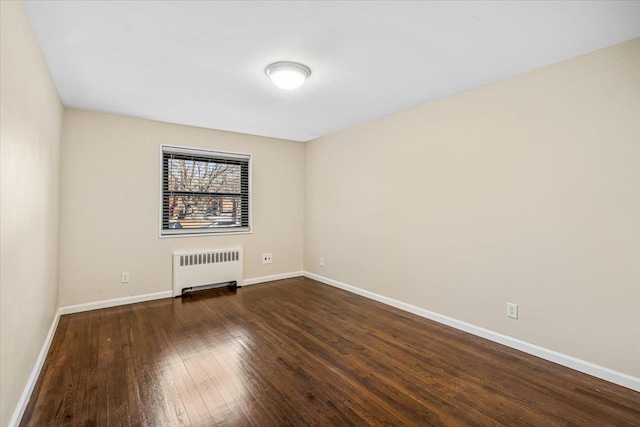 unfurnished room with dark wood-type flooring, radiator, and baseboards