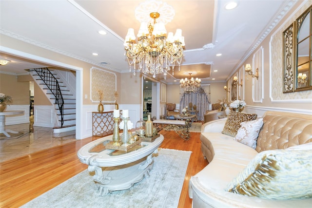 living area featuring wood finished floors, an inviting chandelier, wainscoting, and stairs