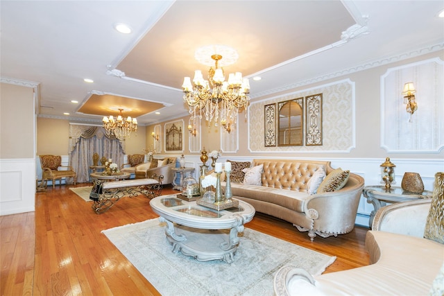 living area with a wainscoted wall, a tray ceiling, crown molding, a decorative wall, and a chandelier