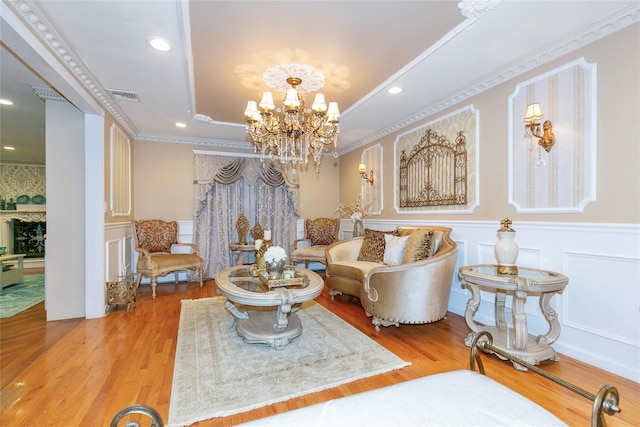 living room featuring visible vents, a chandelier, a tray ceiling, wood finished floors, and a decorative wall