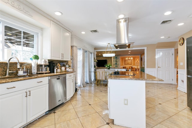 kitchen with visible vents, wainscoting, island exhaust hood, stainless steel dishwasher, and a sink