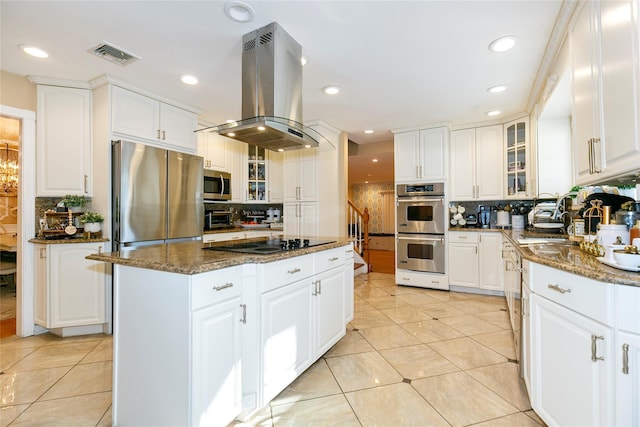 kitchen featuring visible vents, glass insert cabinets, island range hood, stainless steel appliances, and a sink