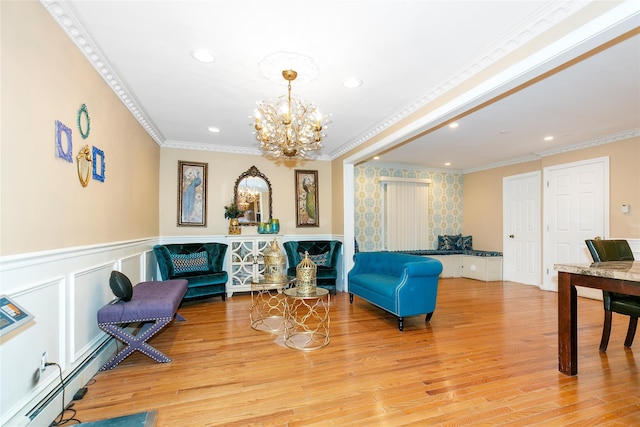 living area with crown molding, a baseboard heating unit, a wainscoted wall, light wood-type flooring, and a notable chandelier