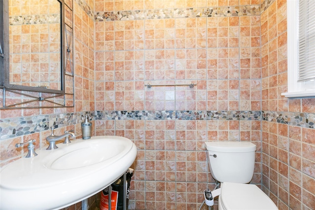 half bath featuring a sink, toilet, and tile walls