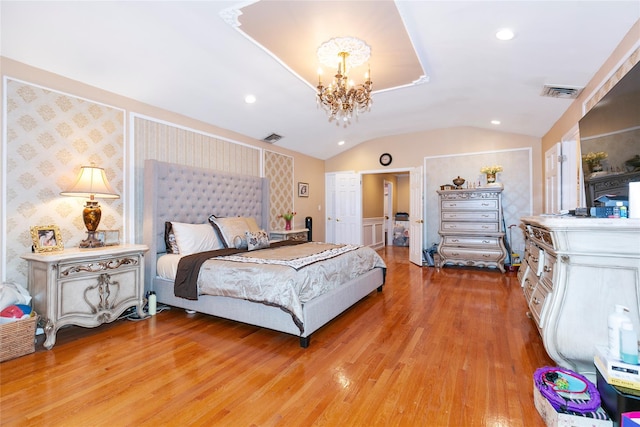 bedroom featuring visible vents, a notable chandelier, light wood-style floors, wallpapered walls, and lofted ceiling