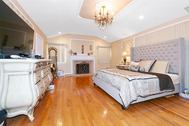 bedroom with a fireplace with raised hearth, vaulted ceiling, recessed lighting, light wood-style flooring, and an inviting chandelier