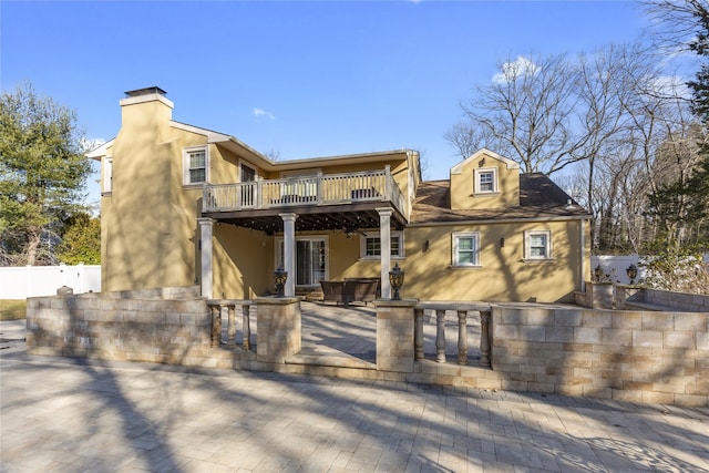 rear view of property with stucco siding, a patio, fence, a wooden deck, and a chimney