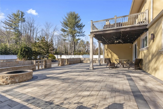 view of patio featuring outdoor dining area, a balcony, a ceiling fan, and fence