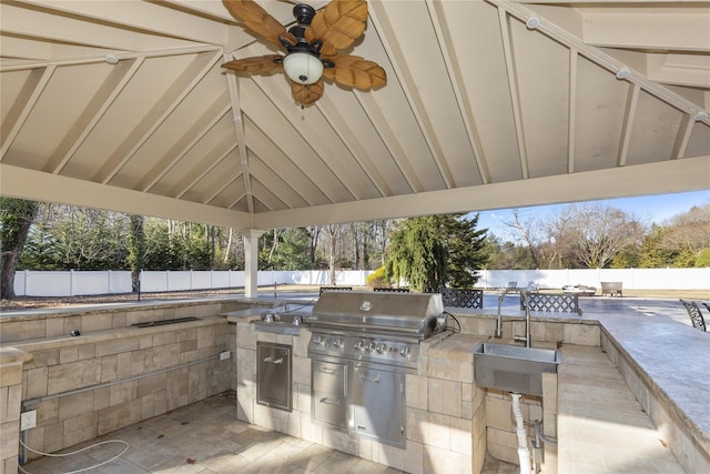 view of patio / terrace with a fenced backyard, area for grilling, an outdoor kitchen, a ceiling fan, and a sink