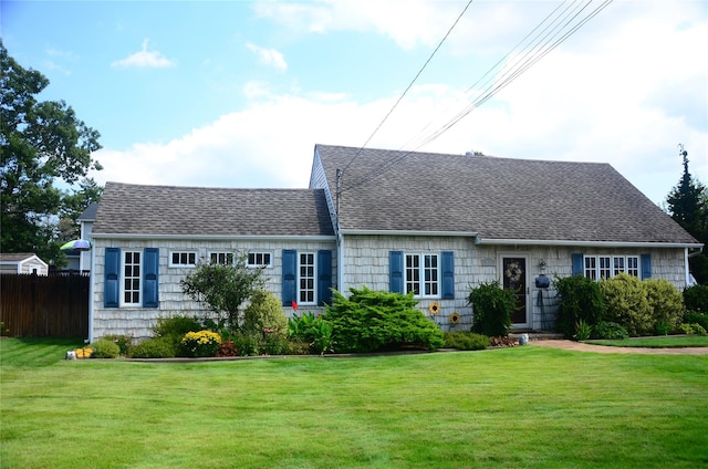 view of front facade featuring fence, a front lawn, and a shingled roof