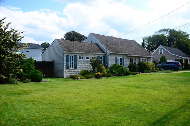 view of front facade with roof with shingles and a front lawn