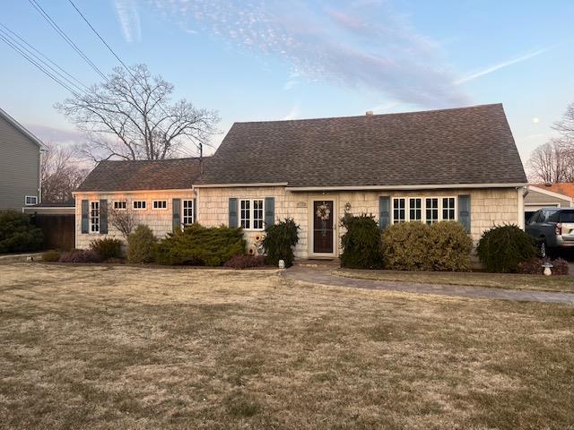 view of front facade featuring a front lawn and roof with shingles