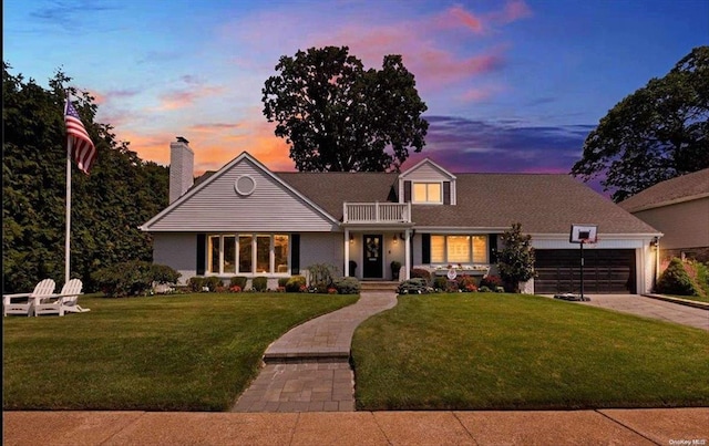 view of front of property with a lawn, an attached garage, driveway, and a balcony