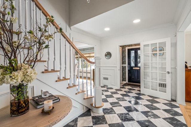 foyer entrance with crown molding, stairway, a decorative wall, and tile patterned floors