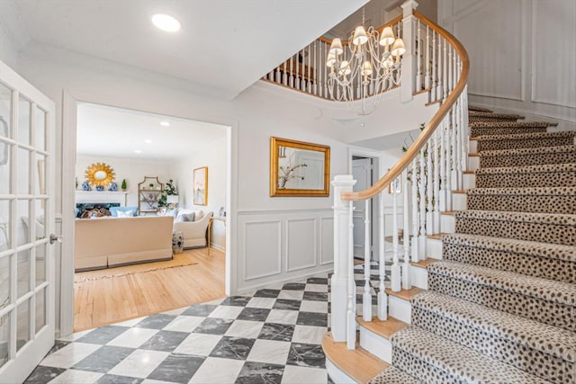 entryway with recessed lighting, stairs, crown molding, a decorative wall, and a chandelier