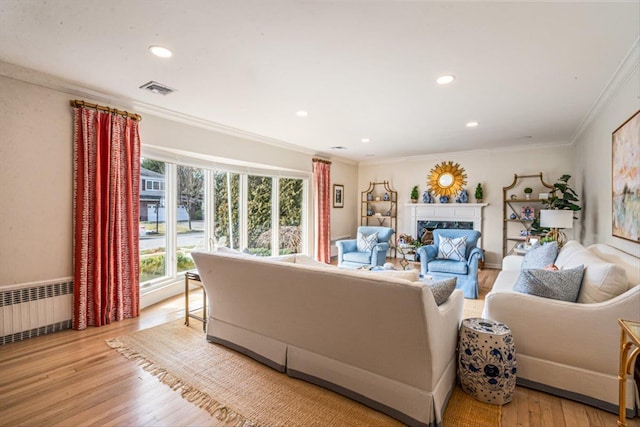 living room with visible vents, crown molding, radiator heating unit, and light wood finished floors