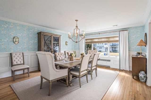 dining room featuring wallpapered walls, an inviting chandelier, ornamental molding, and wainscoting