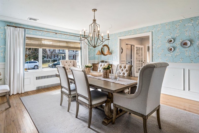 dining space with visible vents, radiator, wallpapered walls, wainscoting, and a notable chandelier