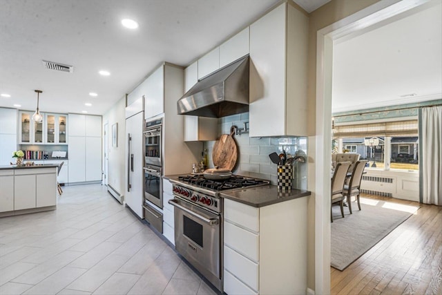kitchen featuring visible vents, radiator heating unit, extractor fan, dark countertops, and high quality appliances