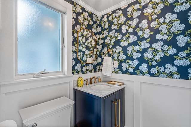 bathroom with crown molding, a wainscoted wall, toilet, a decorative wall, and vanity