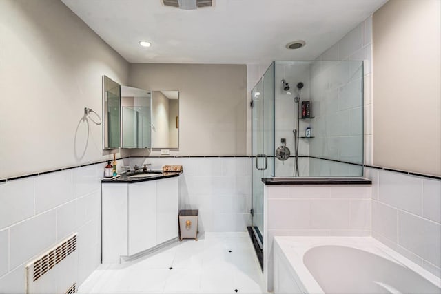 full bath featuring vanity, radiator heating unit, a stall shower, tile walls, and a bath