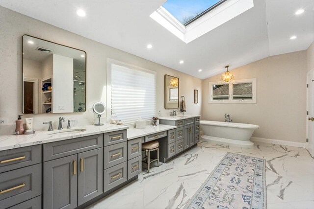bathroom featuring a freestanding tub, marble finish floor, recessed lighting, vaulted ceiling with skylight, and vanity