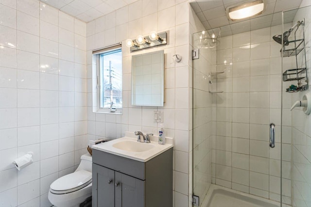 bathroom with vanity, toilet, tile walls, and a shower stall