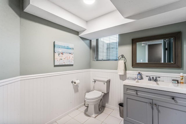 half bath featuring vanity, tile patterned floors, toilet, and wainscoting